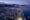 Sunset aerial shot of a small snowy town with a coastline and lots of snowy mountains