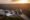 Sunset over Iguazu Falls, a sweeping and dramatic waterfall with miles of lush green rainforest surrounding.