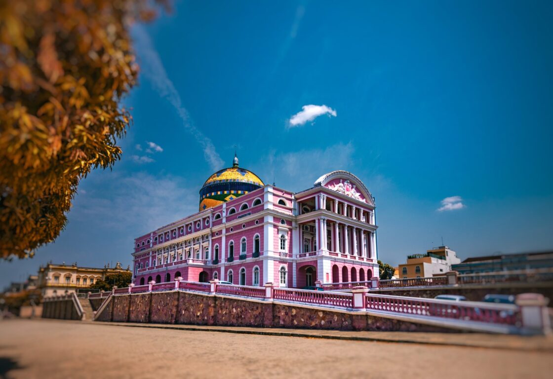 Partial view of the façade and side of the Amazonas Theater on a sunny day with few clouds in the sky.