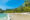 long sandy beach fringed by palm trees and rainforest
