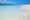 Closeup shot of sea shore with crystal clear blue water meeting wave rippled brilliant white sand