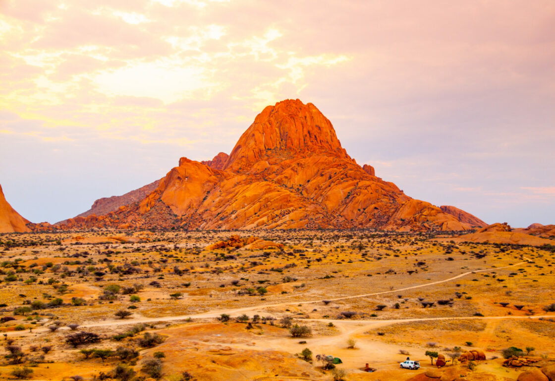sunset wide shot of a red stoned mountain, with desert surrounding