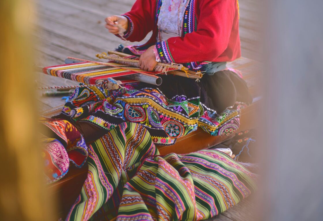 Indigenous woman showing traditional weaving technique and textile making in the Andes mountain range of South America in Peru, Selective focus.
