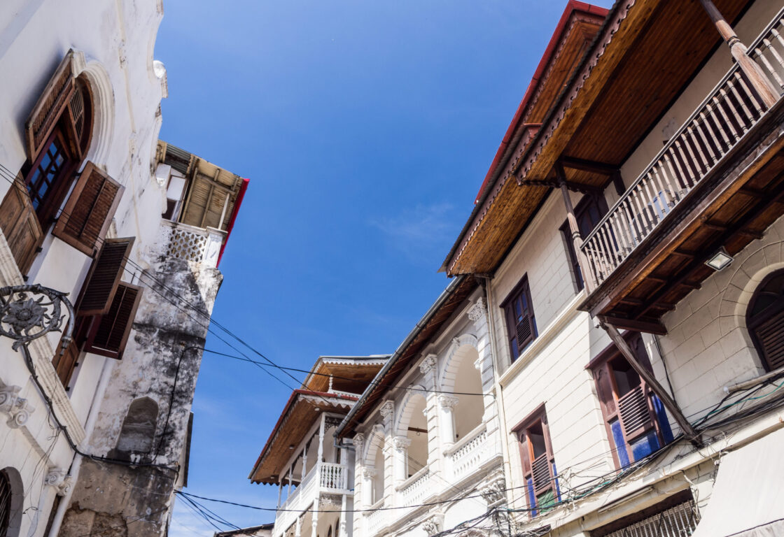 Ground angle shot of a street with old white terraced buildings and a blue sky