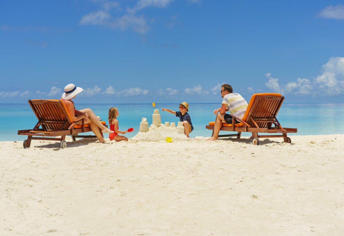 family building a sandcastle at the beach in summer - vacation time