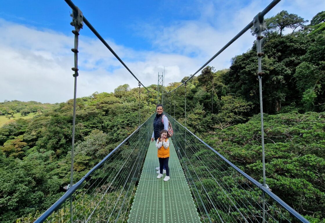 a woman and her daughter standing on a hanging bridge in Costa Rica over the rainforest