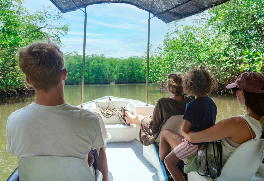 a back view of a family on a boat riding through mangroves exploring the local nature in Costa Rica