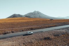 a white car driving through the mountains of San Pedro De atacama Chile