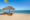 two wooden lounge chairs with blue and white stripy cushions on a Nosy Be beach with straw style umbrella