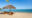 two wooden lounge chairs with blue and white stripy cushions on a Nosy Be beach with straw style umbrella