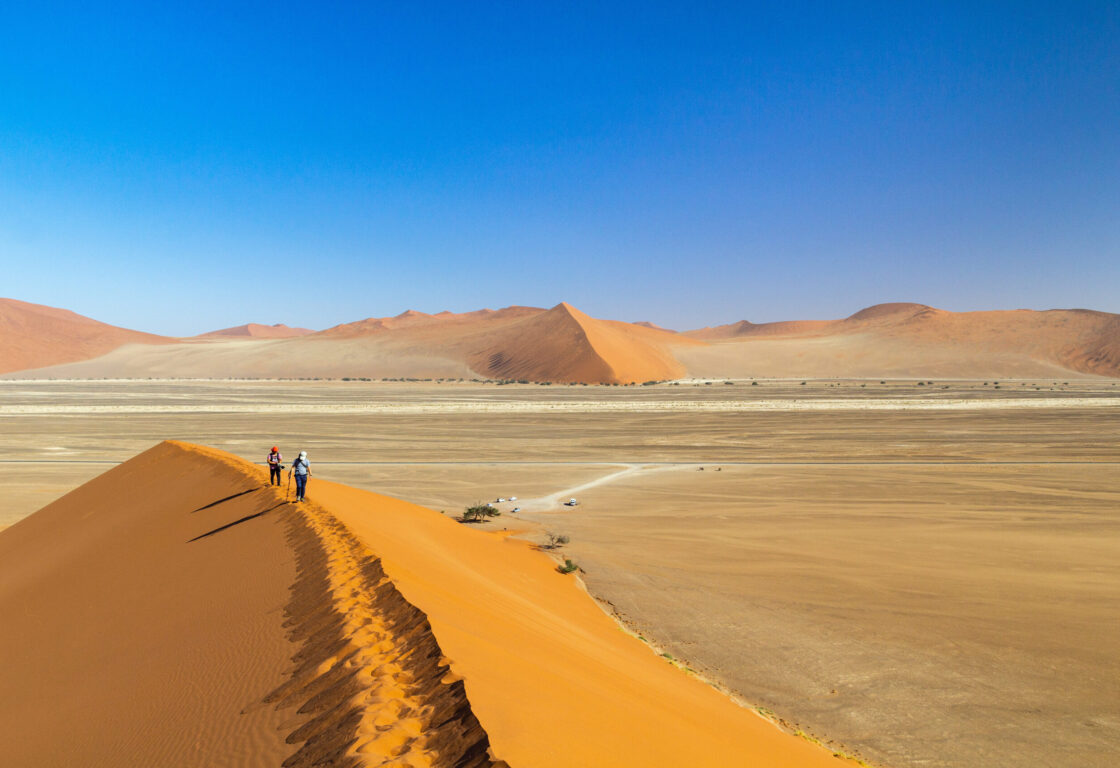 Two hikers walking on the ridge of Dune 45 in the morning light, Namib desert, Namibia