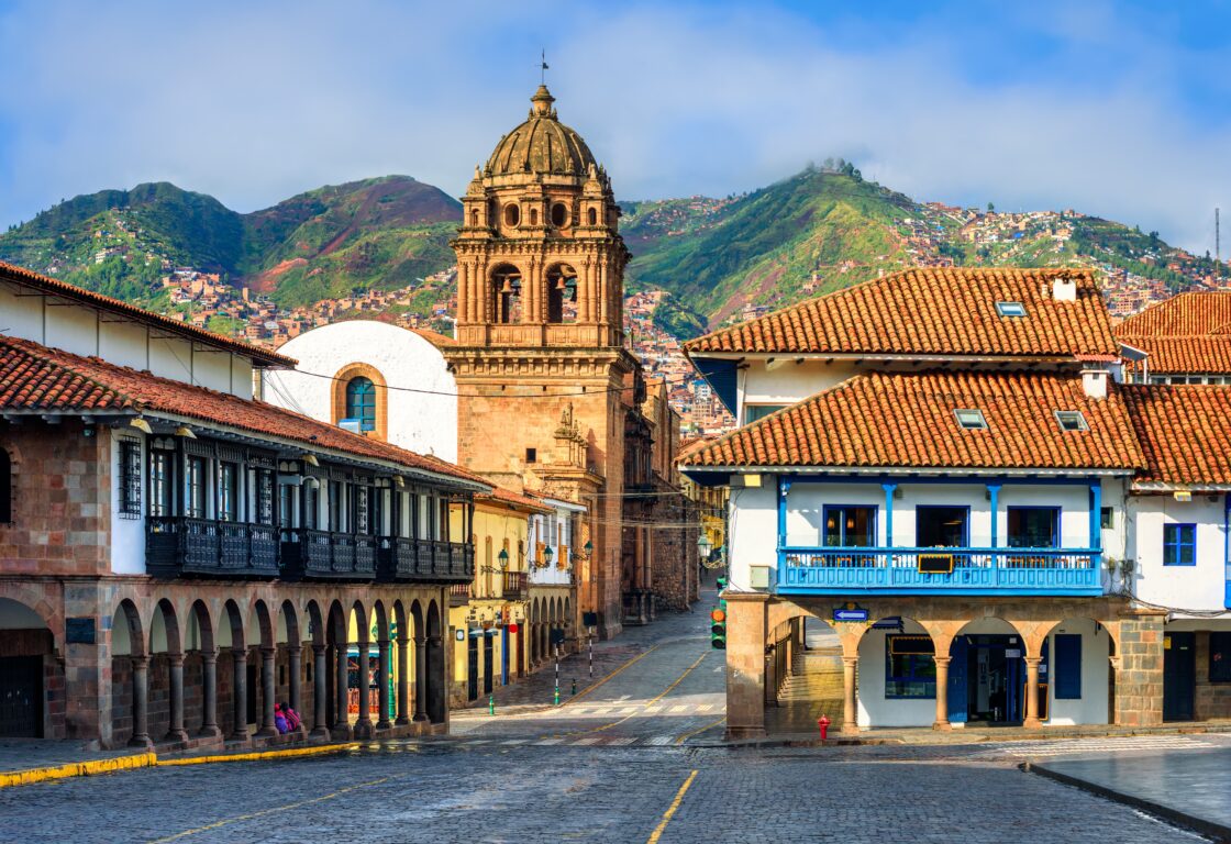 View of the Plaza Mayor and Basilica Menor church in the Old town of Cusco city, and the Andes mountains, Peru. Plaza Mayor is the main square of Cuzco, famous for historical colonial architecture.