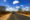 a view of a jeep driving on a road in the middle of a bush in Kruger National Park