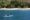Couple kayaking in a bright blue kayak on the clear waters off Tamarindo Beach in Costa Rica, with white sand and lush tropical trees lining the shore in the background.