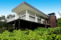 a outdoor view of a Scalesia Galapagos Lodge perched high up in the greenery, the bulding is white and grey, long