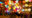 colourful lanterns in various colours and patterns and shapes are hung up at a stall and below them baskets sit on stools and on the floor are the shells of lanterns in a pile