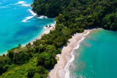 an aerial view of Manuel Antonio beaches with a long stretch of green forest and beach on each side