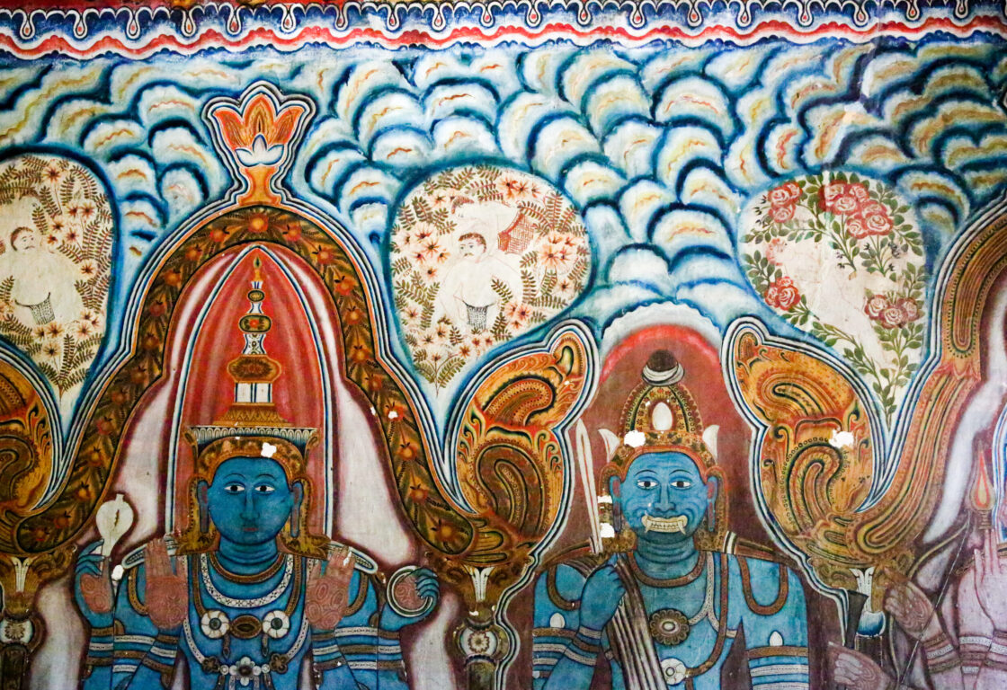 Colourful ancient mural of blue-hued deities and floral patterns at Mulkirigala Rock Temple, Sri Lanka.