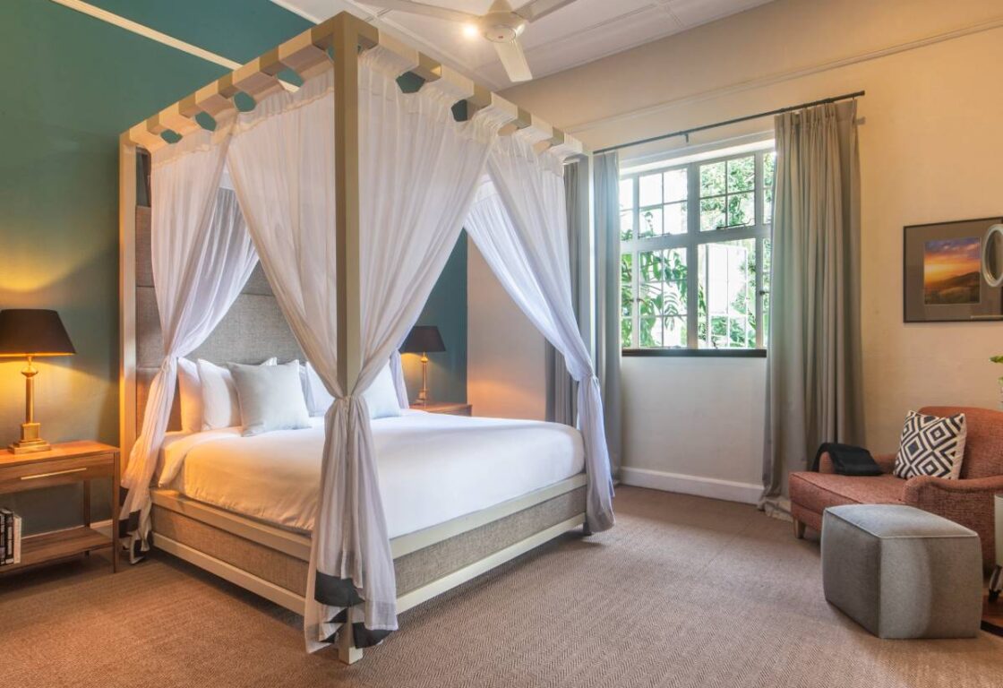 Elegant four-poster bed with soft lighting and heritage styling at Nine Skies, Ella, Sri Lanka.