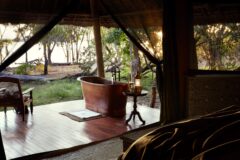 a view from a room onto a terrace with a large copper bath overlooking the nearby lake