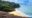 white sandy beach surrounded by rock hills and jungle